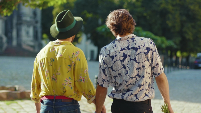 Slow motion young gay couple hold hands hug each other walk at street friendship relationship lifestyle concept homosexual dating intersection travel outdoors lgbt close up