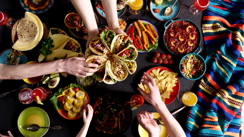 Mexican family celebrates Cinco de mayo. A taco is a traditional Mexican dish consisting of a small corn tortilla topped with a filling | Shutterstock HD Video #1089829103