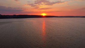 Sun sets over the horizon and the twilight sky is reflected in the ripples of the lake. Footage from a bird's eye view. Ukraine, Europe. Cinematic drone shot. Filmed in UHD 4k video. Beauty of earth.