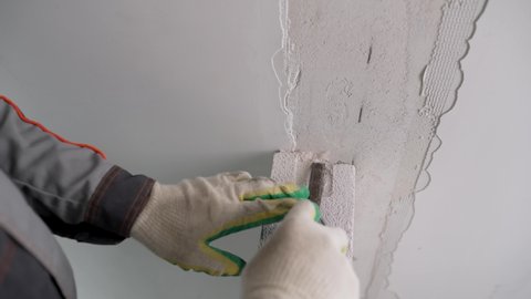 Close-up. A construction worker saws an aerated concrete block with a hand saw at a construction site. The master cuts the construction foam block with a saw. Builders cut the cellular block with a