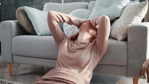 Woman is sitting on the floor and feels tired and hungover due to a headache after an night party. Female person has severe headaches after a drunken night