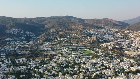 aerial view of Bodrum valley filled with white villas as the sun sets over the hills and homes in Mugla Turkey on a sunny summer afternoon