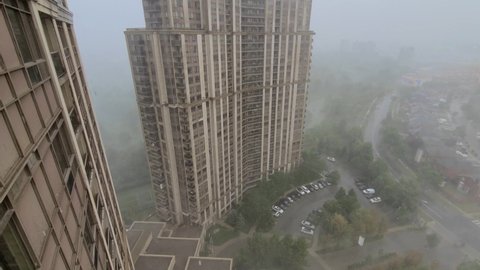 Fantastic powerful wild nature wind and rain storm point of view, looking out of window from high rise building overlooking at hailing weather with hailstones falling and foggy atmosphere.
