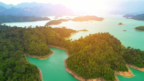 An aerial view from a drone flying over a dam, beautiful turquoise water in a valley. Many small islands and mountains in the background. Ratchaprapha dam, Surat Thani Province, Thailand. 4K
