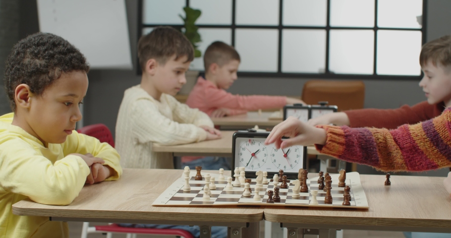Little children playing chess during tournament in club