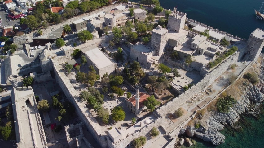 Awesome aerial view of Bodrum Castle in Turkey. Drone flying over the castle. Bodrum Harbor and the port city are visible on scenic mountains background.