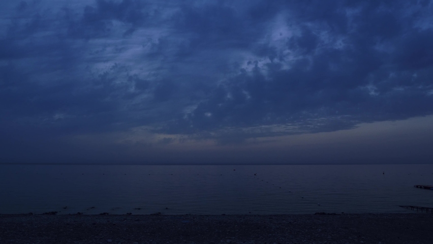 Calm tranquil sea water surface in dusk against cloudy sky. Sunrise over sea. Sky background on sunrise. Wild beautiful nature landscape