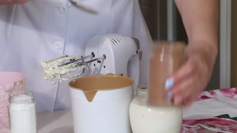 A woman makes cream for eclairs. Adds cocoa powder to it. The ingredients are on the table. Preparing eclairs. Close-up