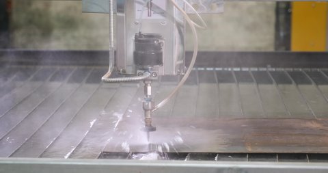 Cutting of metal by waterjet hydroabrasive with water under pressure. Water-abrasive cutting. Modern technologies in industries, manufacturing and metallurgy. CNC water bath machine.