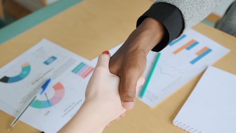 African black man shake hands with his business partner caucasian woman. Handshake when got agreement, deal or signed contract. Diverse business people of different ethnicity and gender. Close-up