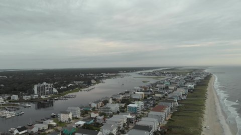 Aerial view of sandy beach, waves, and clouds along Carolina Beach NC houses