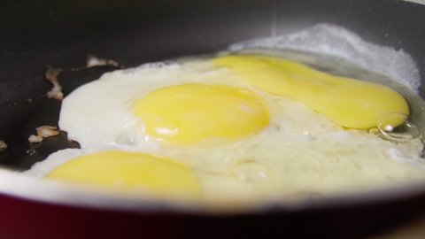 Cooking fried eggs in a frying pan for breakfast. Close up. Slow motion