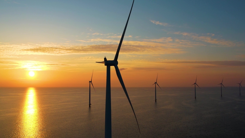 Working offshore wind farm, sunset view. Aerial view of Windpark with wind turbines, windmills. Concept: power plant, climate change, sustainable resources, green energy.