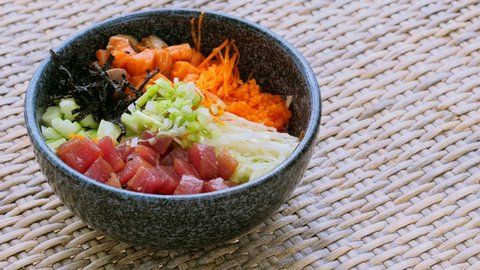 Healthy eating, clean food concept. Fish, vegetables, grains, seaweed. Traditional Hawaiian poke bowl with slices of fresh salmon and tuna standing on the table. Homemade healthy food.