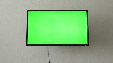 TV mockup screen. LSD smart TV screen with a blank green background in the living room before watching movies and videos on the Internet in 4K. TV television green screen, room, on the wall
