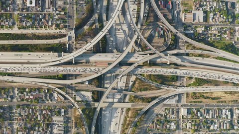 Urban cityscape. Busy traffic highway transportation at downtown Los Angeles streets. Business center of Los Angeles City at golden sunset, USA. Top down aerial of cars drive by multilevel highway