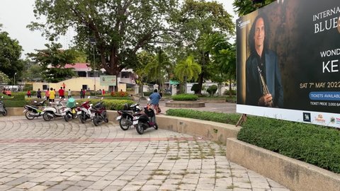 HUA HIN, THAILAND - Circa April, 2022 : KENNY G billboard on sidewalk daytime. Big banner display international jazz and blue festival music show. Famous saxophonist on poster. People exercising
