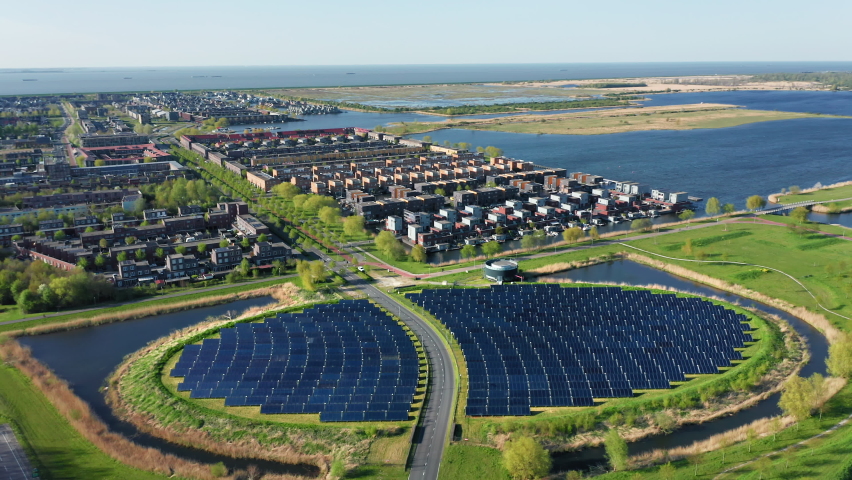 Modern sustainable residential neighbourhood in the city of Almere, The Netherlands, with solar panels farm powering city heating. Aerial view. Royalty-Free Stock Footage #1089853837