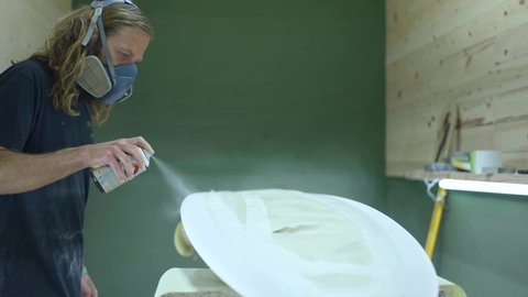 Surfboard making, shaper paints a surfboard. Concept of craftsmanship, small business in America, skilled professional in USA. Surfing industry. 