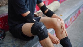 unrecognizable man putting on professional fabric knee pads in a skate park to protect. 4k video