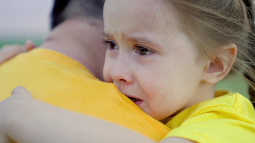 Dad hugs, reassures his little daughter. Baby daughter crying in park in arms of her father. Dad comforts child. Family, child emotionally hug their father with tears in their eyes. Family walk, park Royalty-Free Stock Footage #1089857925