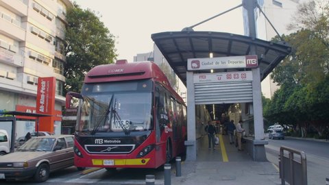 Mexico city - January 13, 2020: panoramic view of a main avenue in Mexico City with a public transport station metrobus in the foreground and the red truck moving forward