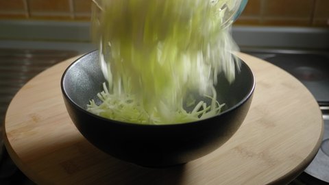 Person pours sliced cabbage into a bowl, cooking delicious scrambled eggs