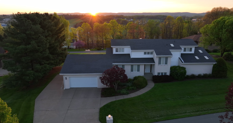 Home on hillside over rural valley. Sunrise over mountains in USA. Colorful trees and warm glow in aerial. House in America during morning.