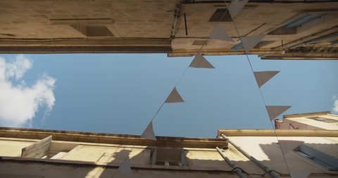 Low angle dreamlike street view of Montpellier France looking up at strings of bunting and blue skies with fluffy white clouds. 