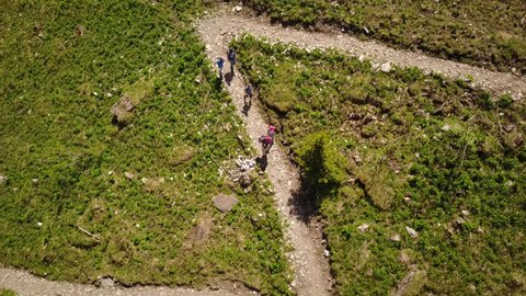 Family hiking in the swiss alps on a gravel path, top view by drone