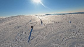 Two guys on snowmobile jumps and rides in the winter at sunlight. Aerial top view in mountains