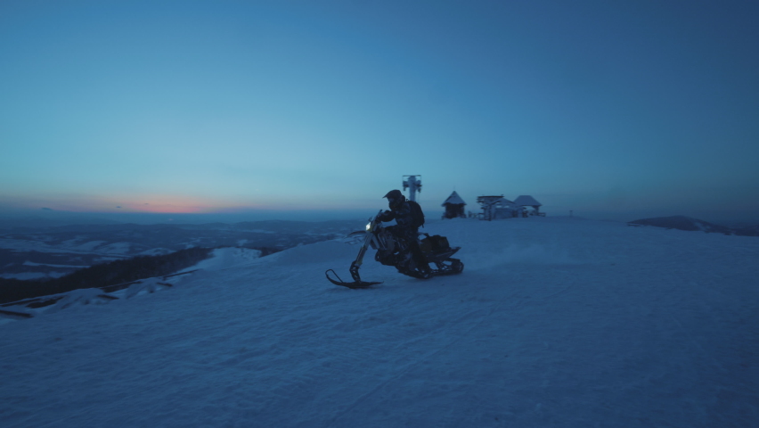 Horizontal footage of fast snowmobile drivers riding snowbikes on background of wonderful mountain slopes. Extreme sport concept. Evening in Carpathian mountains. Ski resort. Ukraine. Adventure