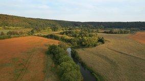The winding river flows through a idyllic green valley. Footage from a bird's eye view. Location place Ukraine, Europe. Cinematic drone shot. Filmed in UHD 4k video. Discover the beauty of earth.