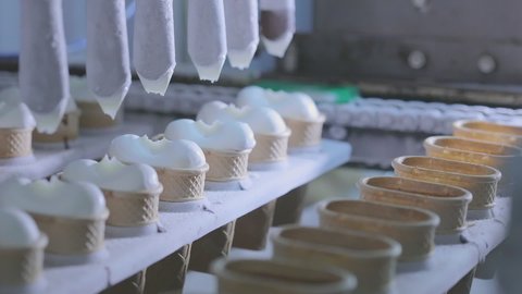 Ice cream is poured into a faffle cup. Ice cream production. Ice Cream Conveyor Line
