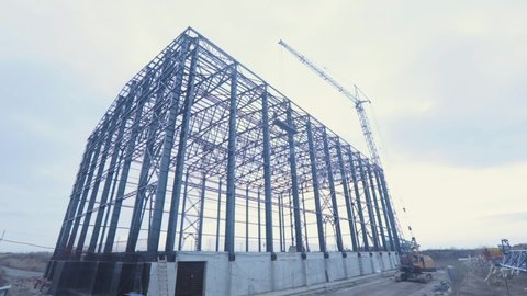 Construction of a large warehouse for a factory. Industrial exterior. Large steel structure building. Metal frame of an industrial building. Construction of an industrial building.