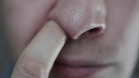 A man picks nasal mucus from his nostrils. Human disease rhinotillexomania, close-up
