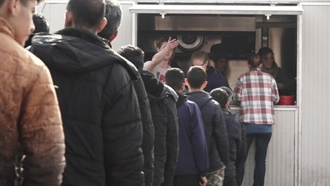 Refugees are standing in line, in front of a food truck with volunteers, providing hot food during the refugee crisis in Europe. Feb 22nd, 2017, Belgrade, Serbia.