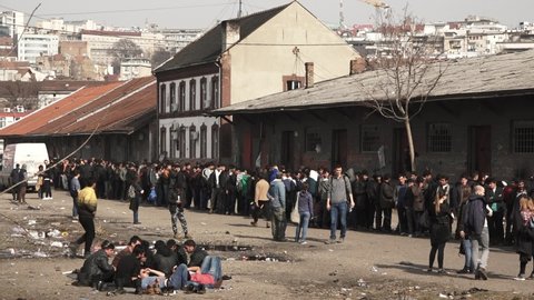 Refugees are standing in line for food in a temporary refugee camp, at an abandoned train station, during the refugee crisis in Europe. some volunteers are visible. Feb 22nd, 2017, Belgrade, Serbia.