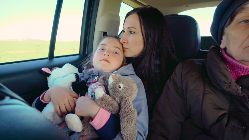 War refugees mother with her daughter and senior woman driving in back seat of car during evacuation from Ukraine. Concept of peaceful and carefree life without armed conflicts Royalty-Free Stock Footage #1089869075