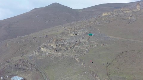 Drone flying toward old watchtower and ruins on top of mountain, fly close to tower, Galiat village, Digoriya gorge, Northern Ossetia, Caucasus, Russia