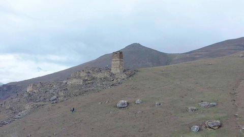 Drone flying counterclockwise around old watchtower and ruins on top of mountain, Galiat village, Digoriya gorge, Northern Ossetia, Caucasus, Russia