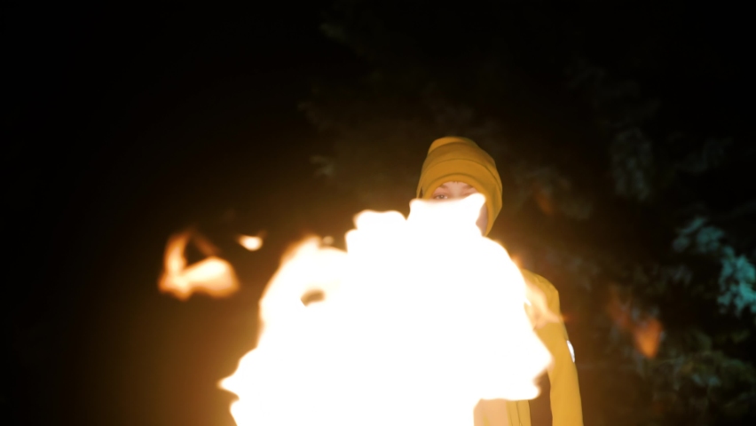 The boy watches the flames of the eternal flame standing in front of him at night. The boy has a thoughtful look