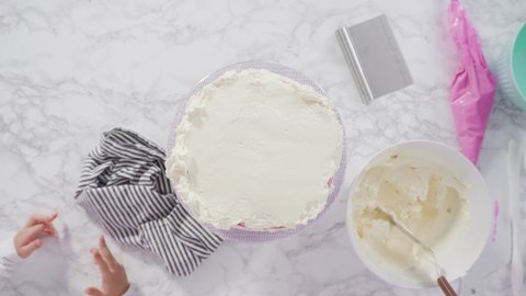 Time lapse. Flat lay. Step by step. Frosting round funfetti cake with white italian buttercream frosting.