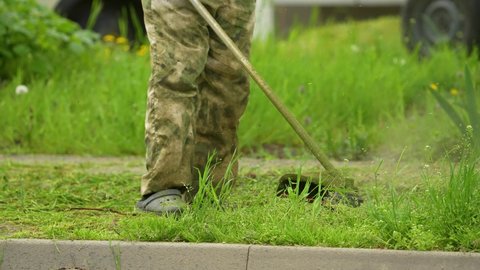 Mikhailovsk, Stavropol region, Russia - May 25 2021: Lawn mowing. A lawn mower shoots grass near the house. Landscape design. Lawn decoration. Green grass. Hard work