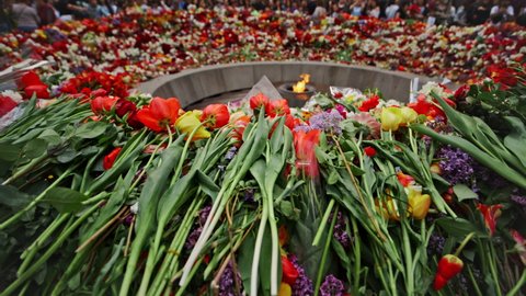 Armenia, Yerevan, The Armenian Genocide Memorial, April 24, 2022 -Lots of multi colored flowers and Armenian flag on the slabs inside the memorial