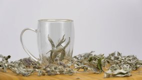 Transparent teapot and tea cup with herbal tea. Breakfast concept. Poring green tea.