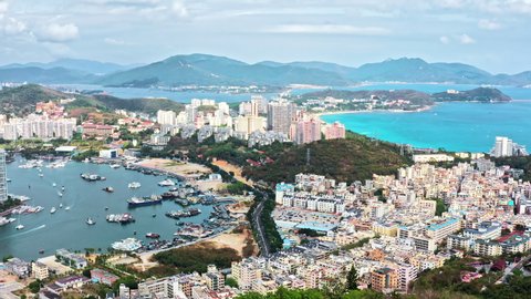 Aerial footage of beautiful city skyline and mountain with sea natural scenery in Hainan Island, China. Drone fly over the city of Sanya. Famous travel destination in China.