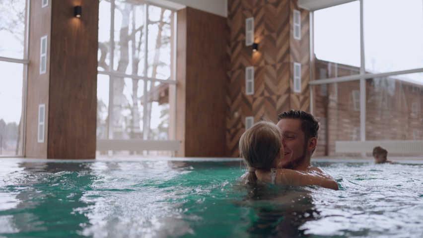 happy little girl is playing with her dad in swimming pool, recreation area and wellness center for family