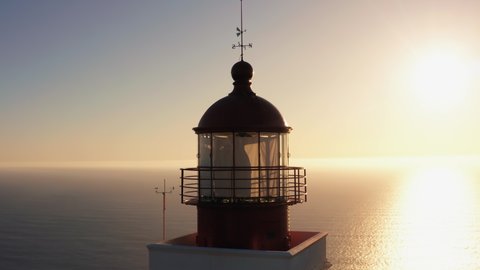 Aerial of sea ocean lighthouse at sunset. Famous landmark at West coast of Madeira island. Orbit shot at low altitude. Waves, sky and horizon line at background.
