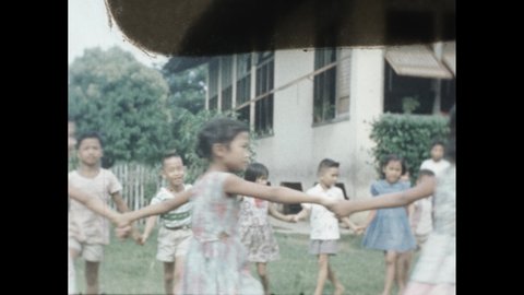 1950s: Children holding hands, walking in circle. Boys playing game in grass. Children playing tug-of-war outside. Boy talking, sitting in classroom.